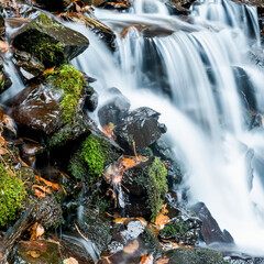 Blurred waterfall throughing mossy rocks