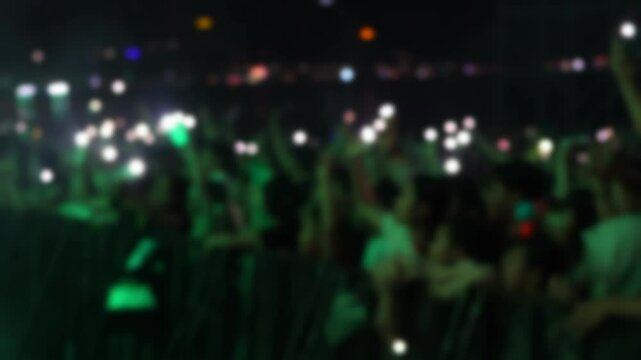 Bokeh view of people dancing on the dance floor during a concert at a festival. Blurred background footage. Concept of crowd enjoying rock and roll, live dj set, hip hop rap party, night club event.