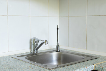 Kitchen sink with tap and filter for drinking water on the background of white tiles