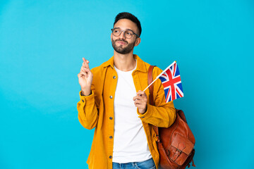 Young caucasian man holding an United Kingdom flag isolated on yellow background with fingers...