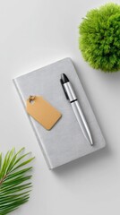 Silver Stylus on Speckled Notebook with Tag near Greenery