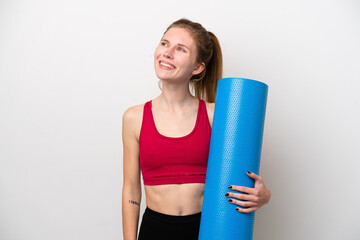 Young sport English woman going to yoga classes while holding a mat isolated on white background...