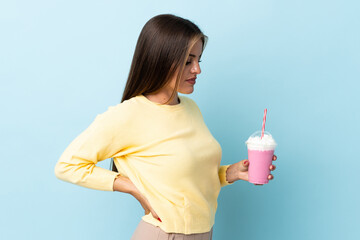 Young Uruguayan woman with strawberry milkshake isolated on blue background suffering from backache...