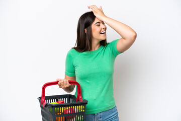 Young Brazilian woman holding a shopping basket full of food isolated on white background has...