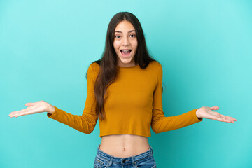 Young French woman isolated on blue background with shocked facial expression