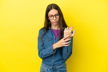 Young French woman isolated on yellow background suffering from pain in hands