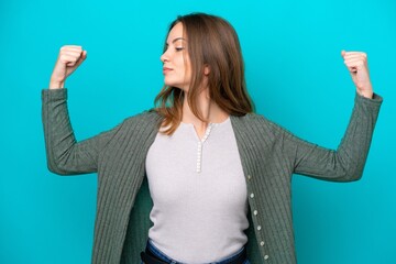 Young caucasian woman isolated on blue background doing strong gesture
