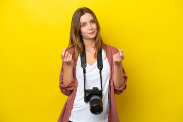 Fototapeta premium Young photographer caucasian woman isolated on yellow background making money gesture