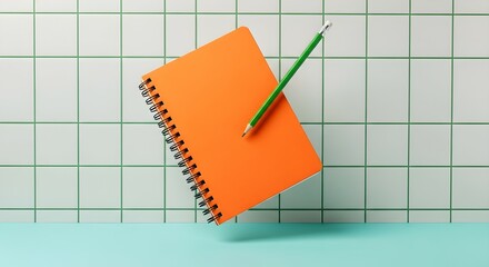 Orange notebook with a green pencil floating above a blue surface on a tiled wall background, creative education concept.