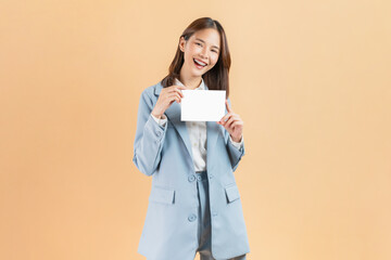 Asian businesswoman holding a blank paper with smiling face and looking at the beige color background, for advertising signs.
