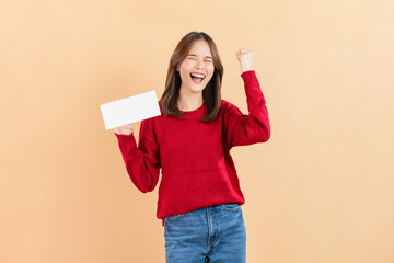 Happy Asian business woman standing and hold gift voucher mock up on beige color background.