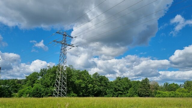 energe comunicative on the street, sky. Tall lattice steel transmission tower carrying multiple power lines stands against a blue sky