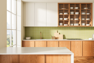 Modern kitchen interior with wooden cabinets, green tile backsplash, and minimalist white...