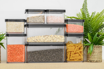 Cereals, pasta, groats and grains in tightly sealed plastic containers on a kitchen shelf