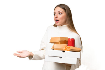 Young beautiful blonde woman holding takeaway food over isolated background with surprise...