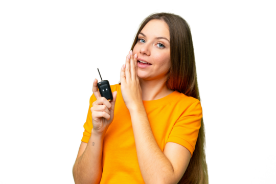Young woman holding car keys over isolated chroma key background whispering something