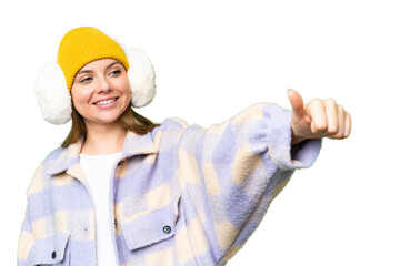 Young blonde woman wearing winter muffs over isolated chroma key background giving a thumbs up gesture