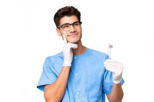 Young dentist man holding tools over isolated background thinking an idea while looking up - Powered by Adobe