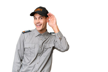 Young security man over isolated background listening to something by putting hand on the ear
