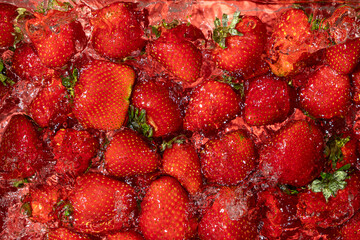 Ripe whole strawberry in water, berry splash, summer background, top view