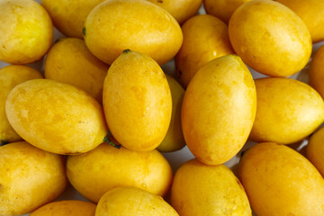 Food texture of Marian Plum, Plum Mango, or in Thailand called Mayongchid. Texture background of yellow skin of fruit. Concept of many, ripe, sweet and sour flavor for wallpaper, print, web.