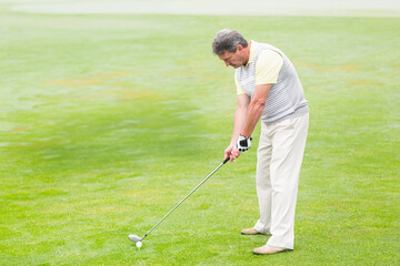 Senior African American man aligning golf club behind ball on tee at golf course, copy space