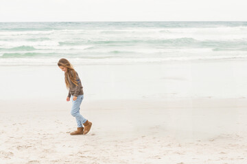 Child girl walking on sandy beach leaving footprints in wet sand near calm waves, copy space