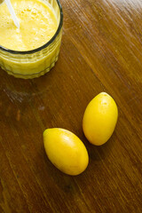 Marian Plum and smoothie placed on wooden table in vertical. Top view two Plum Mango or Thai name...