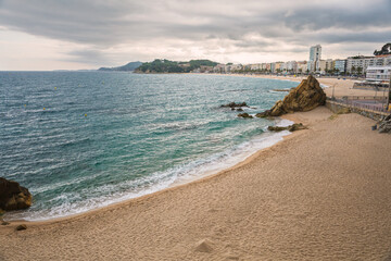 Landscape of Lloret de Mar with Playa de Fenals beach and sea on a cloudy day. Costa Brava coast in Spain.