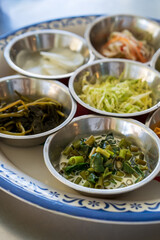 Side dishes for khanom jeen namya by water spinach or morning glory boiled in coconut milk cabbage pickled lettuce radish papaya salad and mixed pickled vegetables in bowl for thai food on vertical