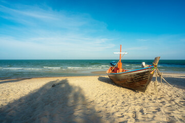 Obraz premium traditional brown fishing boats or small old ancient wooden tourist boat anchored and parked on sand beach of sea island to marine at Hua Hin in Thailand on daylight blue sky for summer holiday travel