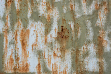 Close-up of a weathered, rust-stained metal surface with peeling paint and corroded textures in...