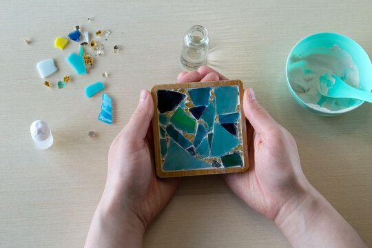 Completed handmade mosaic coaster in mold with dried white gypsum and embedded decorative glass-like fragments viewed from top, step 6