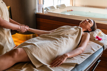 Young woman gets Thai massage on her body by the masseur in the spa salon.