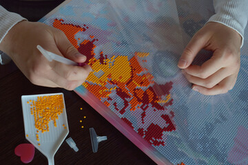 Hands carefully placing colorful beads on a diamond painting canvas creating a vibrant mosaic perfect for DIY art hobbies handmade crafts and creative workshop promotions