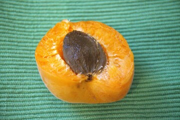 One half apricot with seed close up with green background.