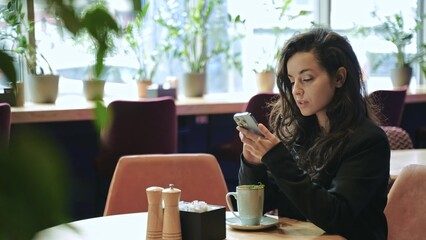 Close-up, slow motion. Caucasian woman sitting inside of cafe, drinking hot tea with mint, and...