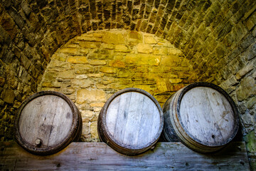 Old wooden barrels stacked against a stone wall in a historic cellar creating an atmosphere of tradition and time-honored craftsmanship