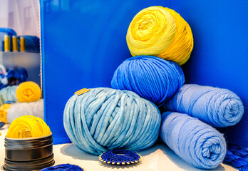 Colorful display of yarn rolls in various shades on a bright blue backdrop in a craft store
