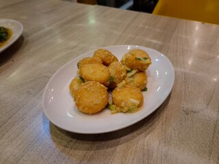 A plate of salted egg cooked tofu served on wooden table