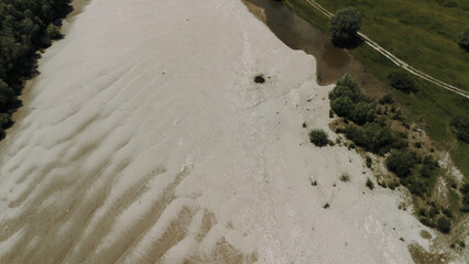Aerial view of a wide sandy beach and nearby greenery on the Danube River near Belegis, Serbia. Circular tire tracks in the sand and the transition between the textured dunes.