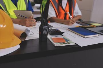 Closeup of team of industrial engineers meeting analyze machinery blueprints consult project on...