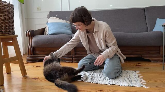 Final bite from cat after playful struggle with owner hands. Woman strokes calms feline, soothing after active predator like play. Affectionate interaction, animal energy, bonding tactile connection