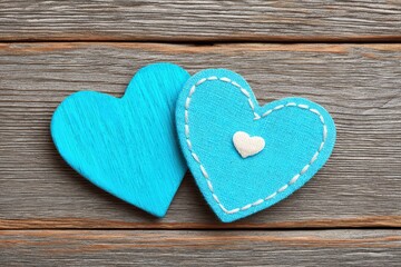 Obraz premium Two intricately designed blue fabric hearts stitched with delicate details resting against a rustic wooden surface symbolizing love creativity and emotional connection in a cozy setting