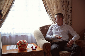 A man sits in a chair with a glass of wine in his hand
