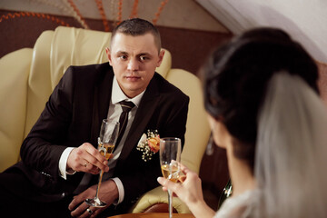 A man and a woman are sitting on a couch, holding glasses of champagne