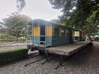 A vintage grey and yellow train carriage, likely a passenger or freight car, is displayed on wooden platform and tracks, perfect for historical transportation themes