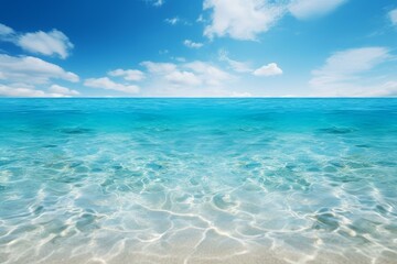 Calm crystal clear turquoise water is meeting the blue sky with white clouds in a sunny tropical paradise