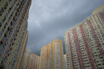 Overcast sky fills the view between tall residential buildings in a densely populated neighborhood,...