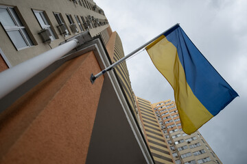 The vibrant blue and yellow Ukrainian flag is displayed prominently on a pole outside a tall...